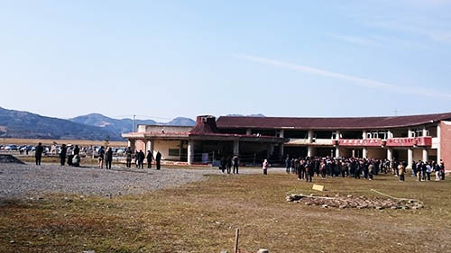 2018年3月11日午後、大川小学校の校舎前で東日本大震災の発生時刻に合わせて黙祷をささげる。年々参列する遺族の数が増えてきているという(筆者撮影)