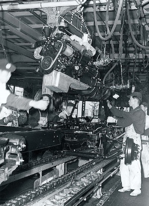 <b>ベルトコンベアの流れに沿って進むエンジンの取り付け作業の様子（挙母工場、1958年頃）</b>（写真提供＝トヨタ）