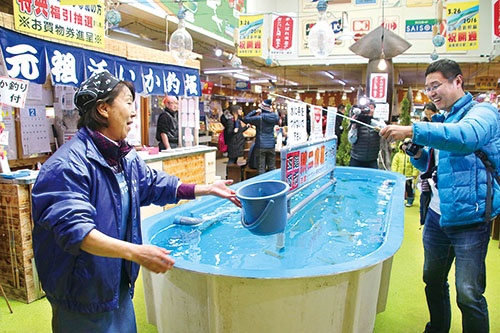 <b>イカの街として知られる北海道函館市。写真は水槽から釣り上げたイカをその場で料理する「活いか釣堀」。イカ料理や珍味を提供する飲食店や土産店が市内に数多くある</b>(写真=共同通信)