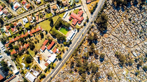 <span class="fontBold"> 南アフリカ、ヨハネスブルクの郊外。道路の左側は白人の中流層が暮らし、右側には失業した金鉱労働者が暮らす。そのほとんどは黒人だ</span>