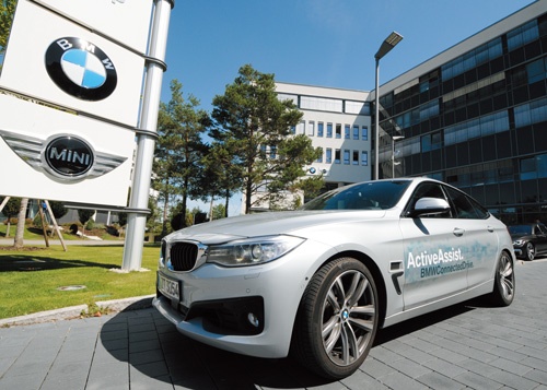 <b>独BMWが初公開した試作車。「PT1」とコードネームで呼ばれている。後ろは同社の研究拠点。駐車場に小型電気自動車「i3」がずらりと並ぶ</b>