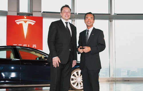 山田喜彦氏（右）はパナソニック在籍時に、テスラとのEV電池の協業を後押しした。2014年9月、日本で初の納車のイベントでマスク氏と（写真＝的野 弘路）