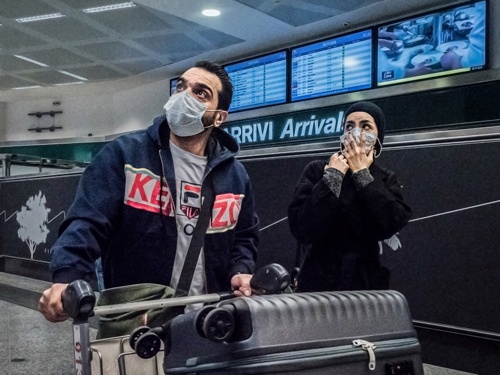 中国からの便でイタリア・ミラノの空港に到着した、マスク姿の乗客（写真：PA Images/アフロ）
