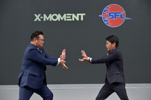 NTTドコモの井伊基之社長(左)とカプコンの辻本春弘社長COO(右)は、互いに向けて「必殺技」を繰り出した。