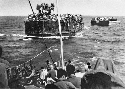 輸送船に引かれて南シナ海を進む難民のはしけ（1975年）（写真：共同通信）