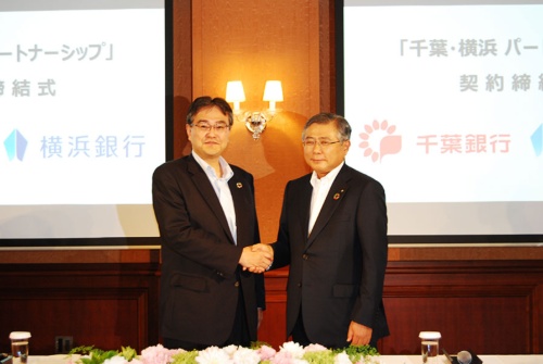 握手を交わした横浜銀行の大矢恭好頭取（左）と千葉銀行の佐久間英利頭取。シナジー効果を出すことができるか、注目が集まる