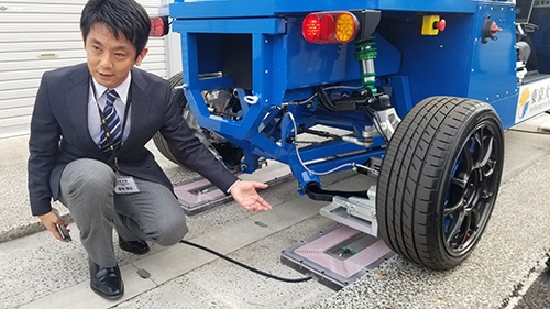 道路に埋め込んだ送電装置から、タイヤで電気を受け取る(左は東京大学大学院の藤本博志准教授)