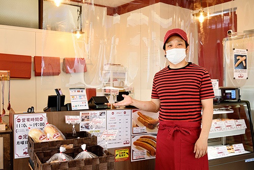 「ソーセージとパンの店 MONJI」の店主、杉本直木さん。お店のレジ前にはビニールパーテーションをして念入りな感染症対策を心掛けているという