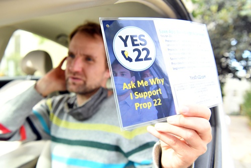 住民立法案「プロポジション22」の賛成派と反対派がそれぞれカードを掲げて自らの主張をアピールした（写真：AFP/アフロ）