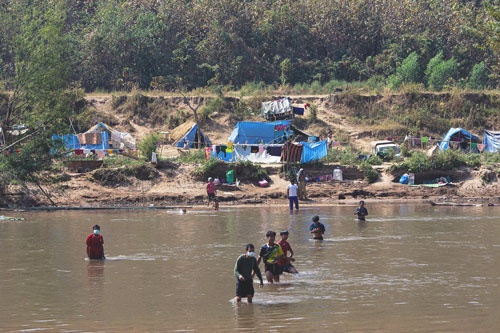 国軍による襲撃を逃れるため、タイとの国境に流れる川を渡って避難するミャンマー人（写真：AFP/アフロ）