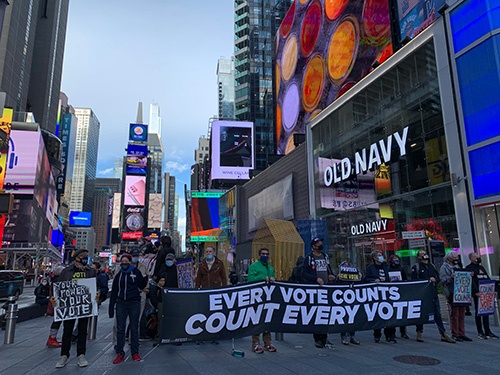 もう少し近づくと、抗議集会の全体像が見えてきた。横断幕には「Count Every Vote（票を残さずカウントせよ）」との文字が書かれていた