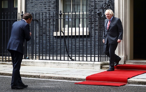 フランスのマクロン大統領は6月、ジョンソン英首相との会談で、新型コロナウイルス対策として慣れないお辞儀で挨拶をした（写真：代表撮影／ロイター／アフロ）