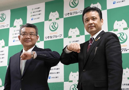 肘タッチする関西みらいフィナンシャルグループの菅哲哉社長(左)と、りそなホールディングスの南昌宏社長(写真:共同通信)