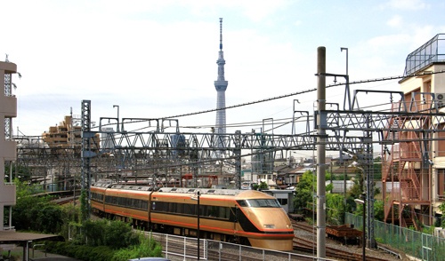 東京スカイツリーと鐘ケ淵駅付近を走る東武鉄道の列車