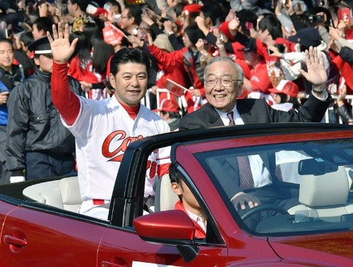 16年、セ・リーグ優勝を祝うパレードでファンに手を振る。右は松田元オーナー(写真:共同通信)