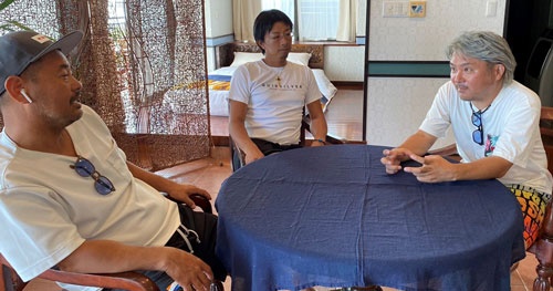 ホテルの部屋でオーナーと相談する酒匂さん(右)と平良さん(左)