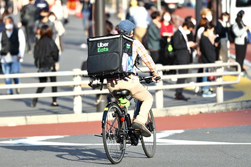 自転車で注文者の自宅や職場に向かう「ウーバーイーツ」の配達員（写真：西村尚己／アフロ）