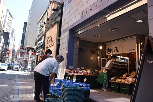オフィスや飲食店が立ち並ぶ旬八青果店の赤坂店。店先にはモモやスイカなどが並び、利用客が品定めしていた