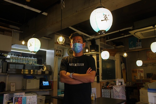 JR横浜駅近くに立つ、まるう商店の杉原昌和氏。新商品のジャパニーズジン「翠」の普及に全面協力する