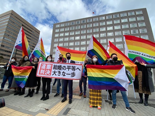 「同性婚を認めないのは『違憲』」との判決が出たことを示す横断幕とレインボーフラッグを掲げる札幌の弁護団と支援者たち