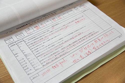 現場の状況を記録した社員の報告書に毎日、赤ペンでコメントを書きこむ( 写真:的野弘路)