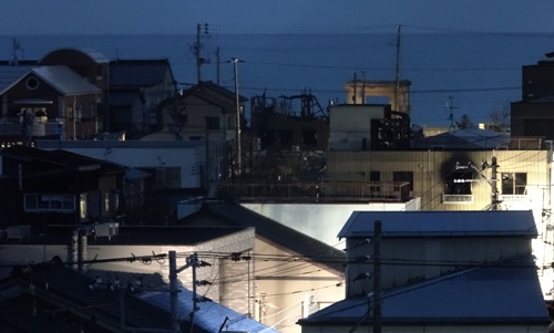 2016年12月26日、新幹線ホームから日没後の「糸魚川駅北火災」の現場を望遠レンズで撮影。明るい場所はインフラ復旧工事現場だ。その向こうが日本海。（写真・山根一眞）
