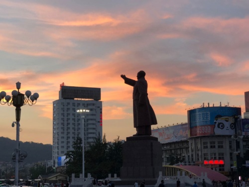 丹東駅前で夕陽に浮かび上がる毛沢東の巨大な像（筆者撮影）