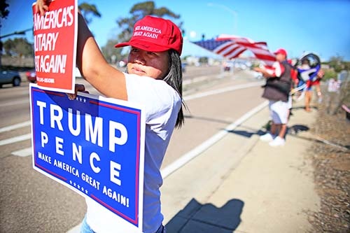 米大統領選でドナルド・トランプ氏が勝利をおさめた後、勝利を喜ぶトランプ氏支持の若い女性。掲げたカードや帽子には「MAKE AMERICA GREAT AGAIN！（偉大なアメリカを取り戻す）」の文字。（写真：ロイター／アフロ）