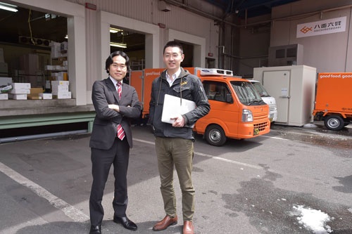 本社オフィスがある物流倉庫前に立つ斎藤事業統括本部長(左)と松田社長(右)(写真:菊池一郎)