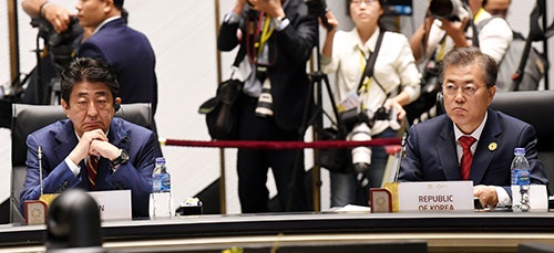 安倍首相（左）は自民党議員などからの反発を覚悟の上で、平昌五輪開幕式に参加する意向を固めた（写真：YONHAP NEWS/アフロ）