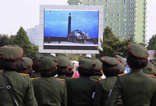 「火星12」とされる弾道ミサイル発射のニュースを見るために、北朝鮮・平壌駅前の大型スクリーン前に集まった人々。ミサイルは日本の上空を通過した。（写真：AP/アフロ）