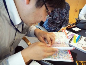 『ハンディマップル 詳細便利地図』をめくる昭文社の市川さん。後編はこちらの、ポケットサイズの地図のお話です