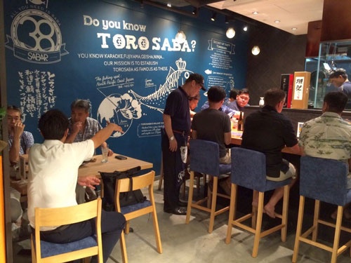 現地客で賑わう「SABAR SINGAPORE」。店内の黒板で、「とろさば」がおいしい理由を説明している