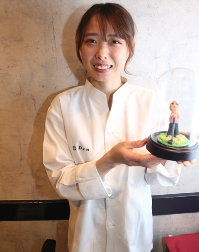 パティシエ歴5年の今野（こんの）真子さん。手に持っているゴルファー風人形は、お客様の誕生日ケーキのために彼女が作った菓子細工のデコレーションだ