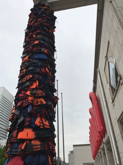 ヨコハマトリエンナーレ2017の会場の一つ、横浜美術館では、館内に入る前に正面入口付近で中国の美術家アイ・ウェイウェイの作品《安全な通行》や《Reframe》が見られる。この二つは、ギリシャのレスボス島にたどり着いた難民が着ていた約800着の救命胴衣や救命ボートを使った作品だ。「 難民問題の一端をリアルに表し、私たちの日常生活とつなげている」（同トリエンナーレのコ・ディレクター、三木あき子氏）という