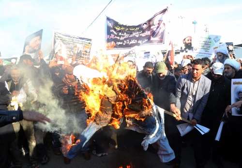 シーア派の有力な宗教指導者ニムル師の死刑執行に抗議して、サウジのサルマン国王の肖像に火を付けるイラクの人々（写真：AP/アフロ）