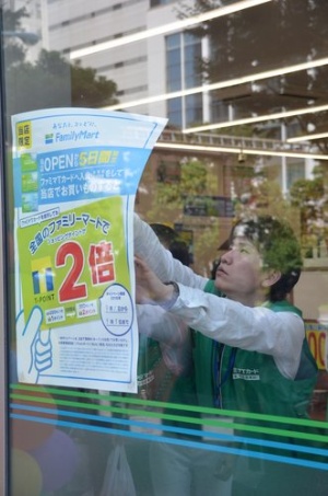 Tポイント対応カードの登録募集ポスターを掲示するファミマのスタッフ（9月1日、東京都中央区）