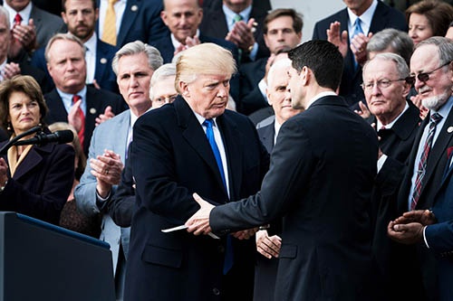 米下院は12月20日、約30年ぶりの大規模な税制改革法案を可決した。税制改革法案の可決を喜ぶ米下院のポール・ライアン議長(中央右)と握手をするトランプ大統領 (写真:AP/アフロ)