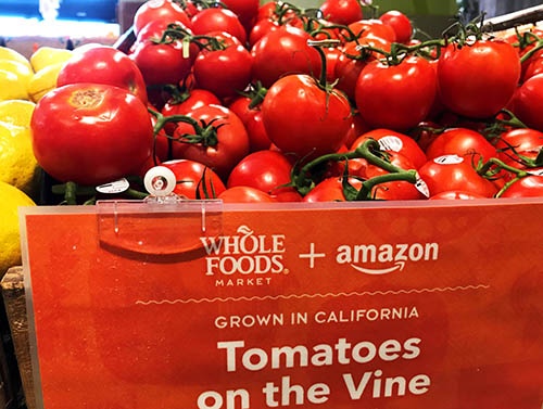 米アマゾンによる買収で話題になった高級スーパーマーケットチェーン「ホールフーズ・マーケット」の店頭。トマトを売る台にも「amazon」の文字が。アマゾンはホールフーズの商品を短時間で顧客に届けるサービスを一部店舗で始めている（写真：ロイター/アフロ）