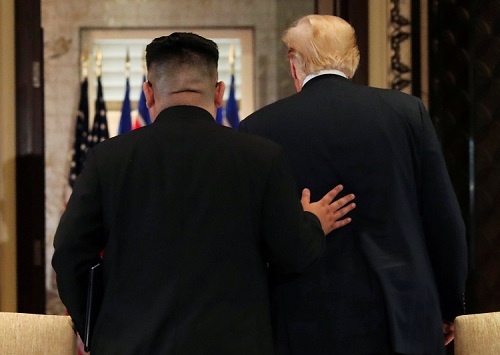 米朝首脳会談で合意文書に署名後、トランプ大統領の背に手を添える金委員長（写真：ロイター/アフロ）