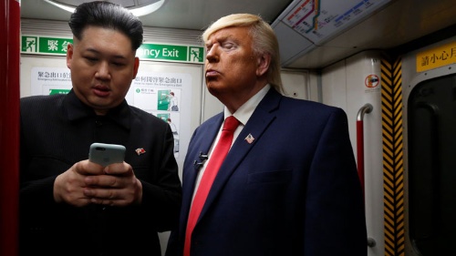 香港の地下鉄での広告でスマホをいじる偽委員長と、覗き込む偽大統領(写真:ロイター/アフロ)