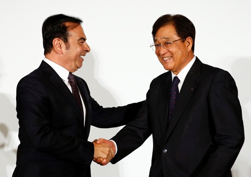 提携発表で握手する日産自動車のカルロス・ゴーン社長（左）と、三菱自動車工業の益子修会長（写真：ロイター/アフロ）
