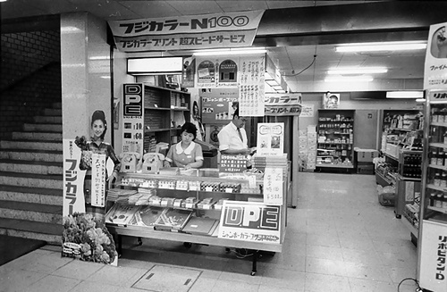 日本ジャンボーとして集中ラボ方式を確立し、クリーニング店やタバコ店などの取次店を開拓。1991年には店頭（現ジャスダック）市場に株式を上場。96年9月期の売上高は約160億円、取次店は最大約6万店まで拡大した。写真は1960年代の日本ジャンボーの直営取次店