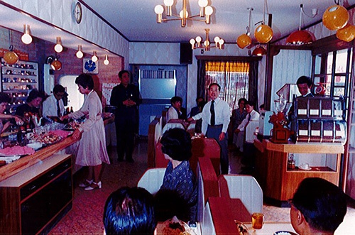 1974年に妻の直美氏(立っている女性)と喫茶店「バッカス」を開業。右下の後ろ姿の男性が宗次氏