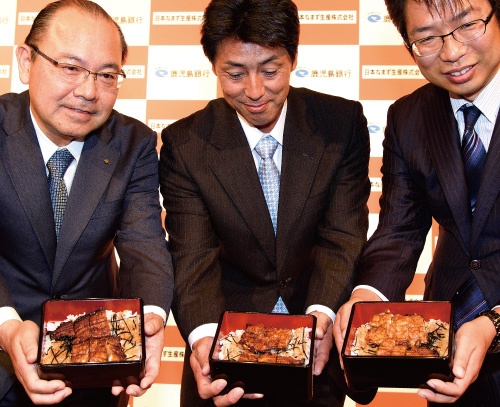 「ウナギ味のナマズ重」を披露する日本なまず生産の牧原博文社長(中)、有路昌彦取締役(右)ら(写真=宮田 昌彦)