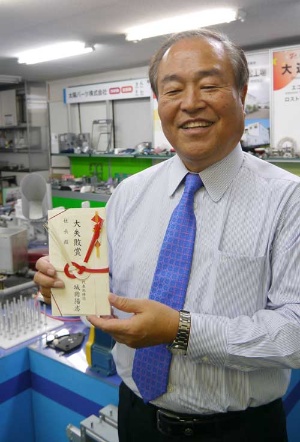 自分が選ばれた「大失敗賞」の目録を持つ城岡陽志社長