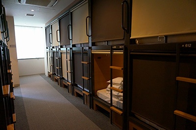 「グリッズ日本橋イースト」の「デザイナーズPOD」（２段ベッド）タイプの部屋（1泊3300円）。二段ベッドはきしみ音がないように特注スチール、密閉性の高いロールカーテンを使用し、鍵のかかる大型ロッカーもある