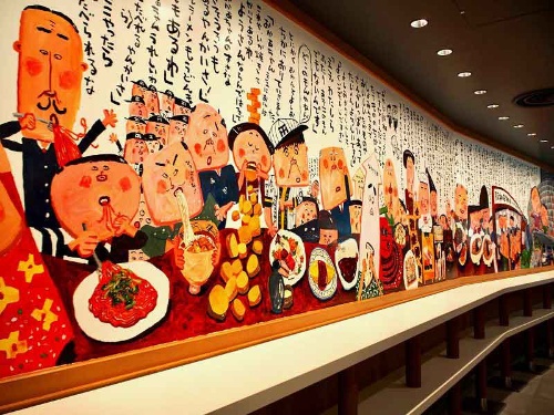 スナックパークの壁面カウンターには絵本作家・長谷川義史氏が描いた幅約10メートルの巨大壁画が展示されている