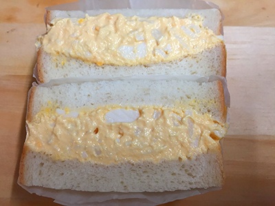 ニュウマン新宿のエキナカにある「Wa’sサンドイッチ」の看板メニュー「煮たまごサンド」（税込み500円）。カツオと昆布のだしがしっかりしみた特製の煮卵を使用したサンドイッチ。見た目は普通だが、かむとだしのうまみが広がるインパクトのある卵サンド