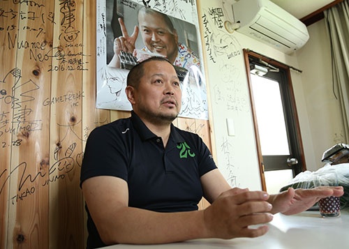 個人商店の光山英明社長。運営する肉料理専門店「肉山」の壁には、来店した有名人のサインがすき間なく並ぶ(写真:陶山勉、以下同)